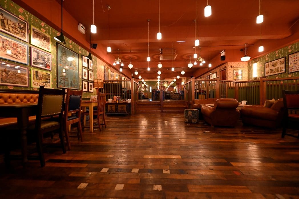 A warmly lit restaurant, Alento features wooden floors, eclectic furniture, framed art on green walls, pendant lights hanging from the ceiling, and a cozy, inviting atmosphere.