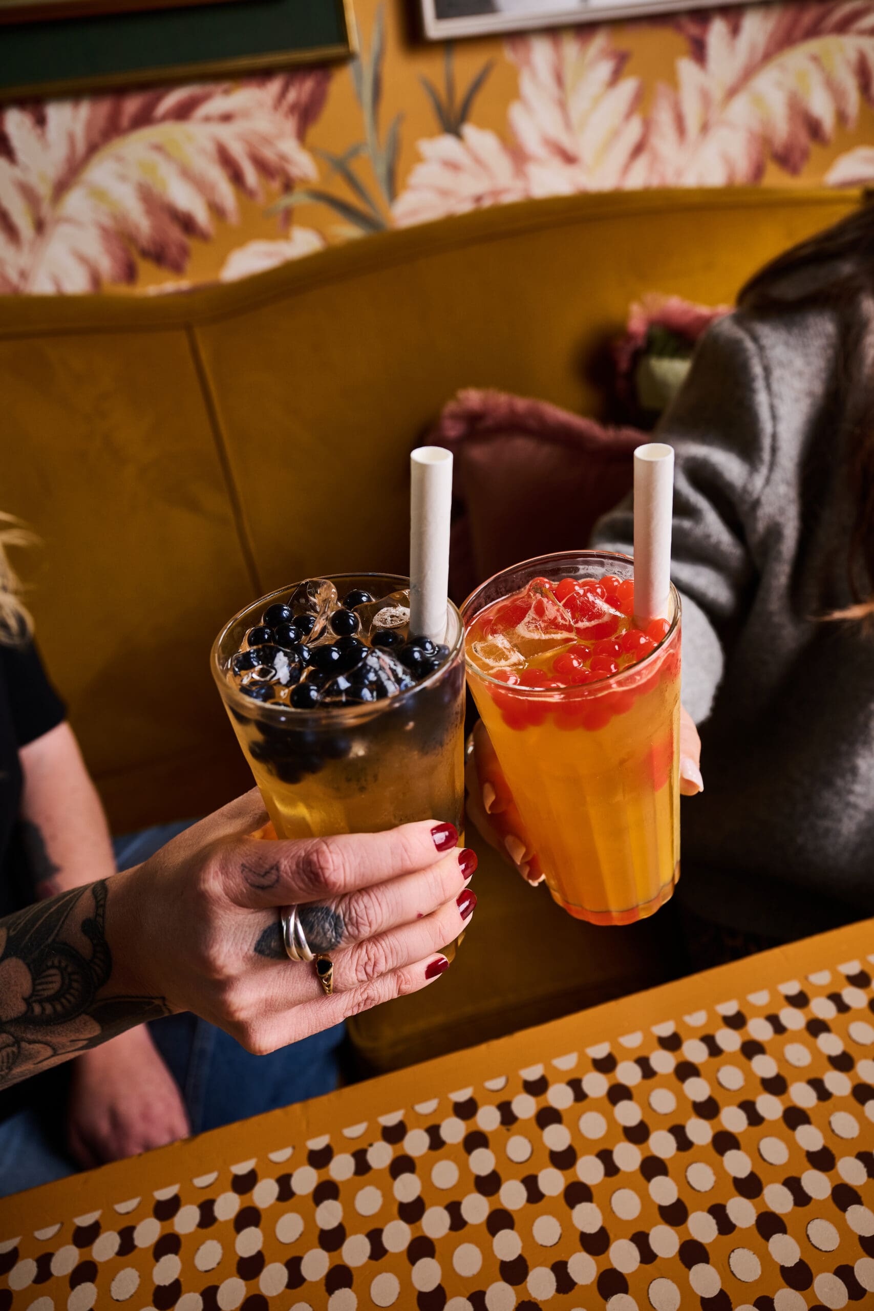 Two hands holding drinks with straws.