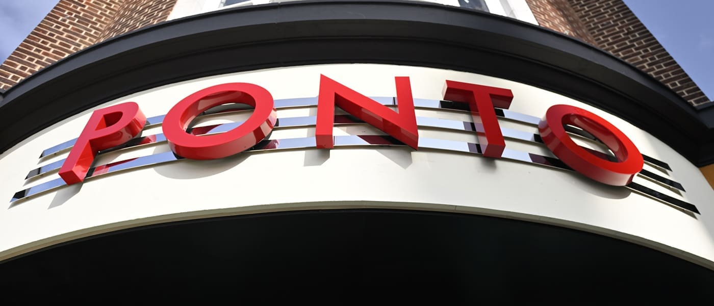 The image shows a building sign displaying "PONTO" in large, bold red letters above a curved awning with metallic horizontal lines. The Ponto building features classic red brick and crisp white trim.